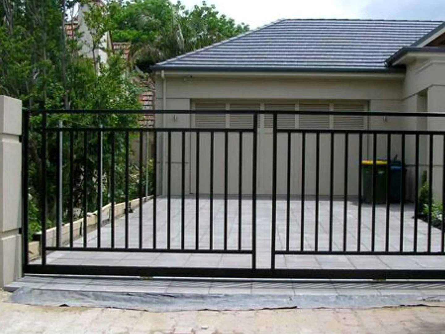 Site ve apartman dekoratif demir çit uygulaması; konut girişinde çift kanatlı açık görüşlü dikey metal profil kapı ve çevreleme