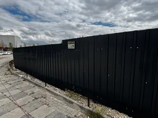 Uzun inşaat parsellerinde siyah trapez sac saha kapama.